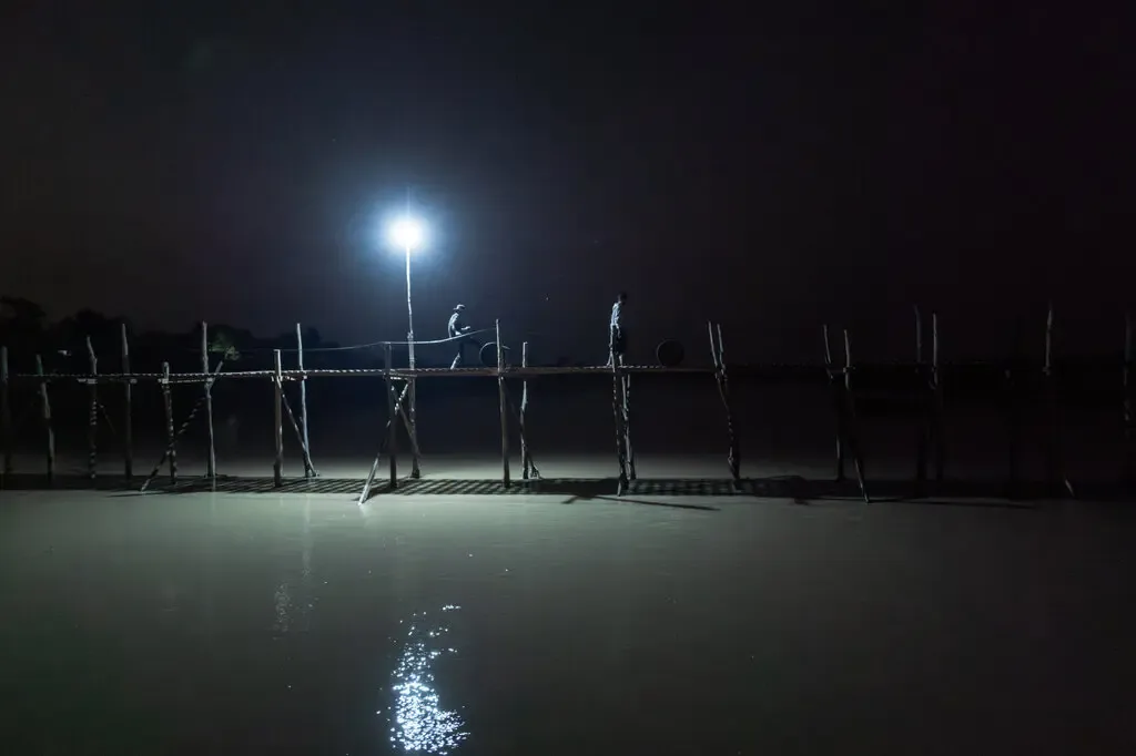 Gece vakti, uzak köylere yakıt sağlamak amacıyla küçük bir köprüden varil varil itiliyor. Karanlık, Myanmar ordusundan bir nebze de olsa saklanma imkanı sağlıyor.